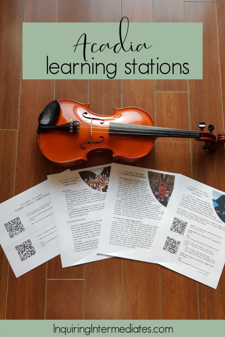 Acadia learning stations. A fiddle lays flat on a wooden floor. Underneath it, there are several articles about Acadian culture. They feature colourful pictures and QR codes to useful videos about Francophone cultural traditions.