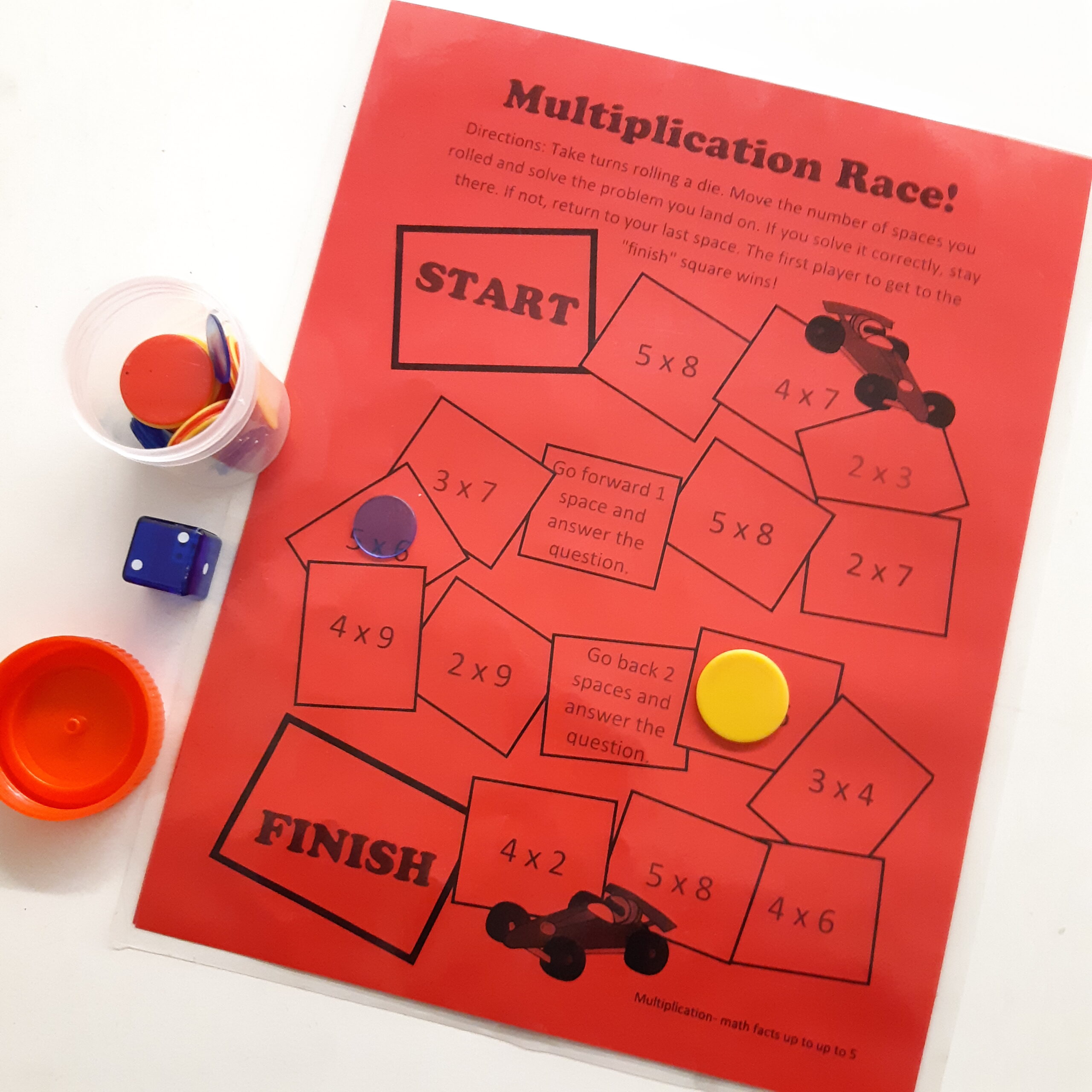A urine sample jar with counters in it sits beside a red math game and blue die.