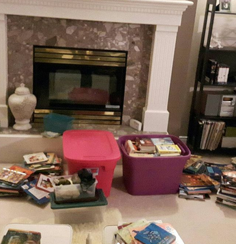 Two giant Rubbermaid bins full of my classroom library books. Other books are strewn on the floor by the fireplace and all over the beige carpet.