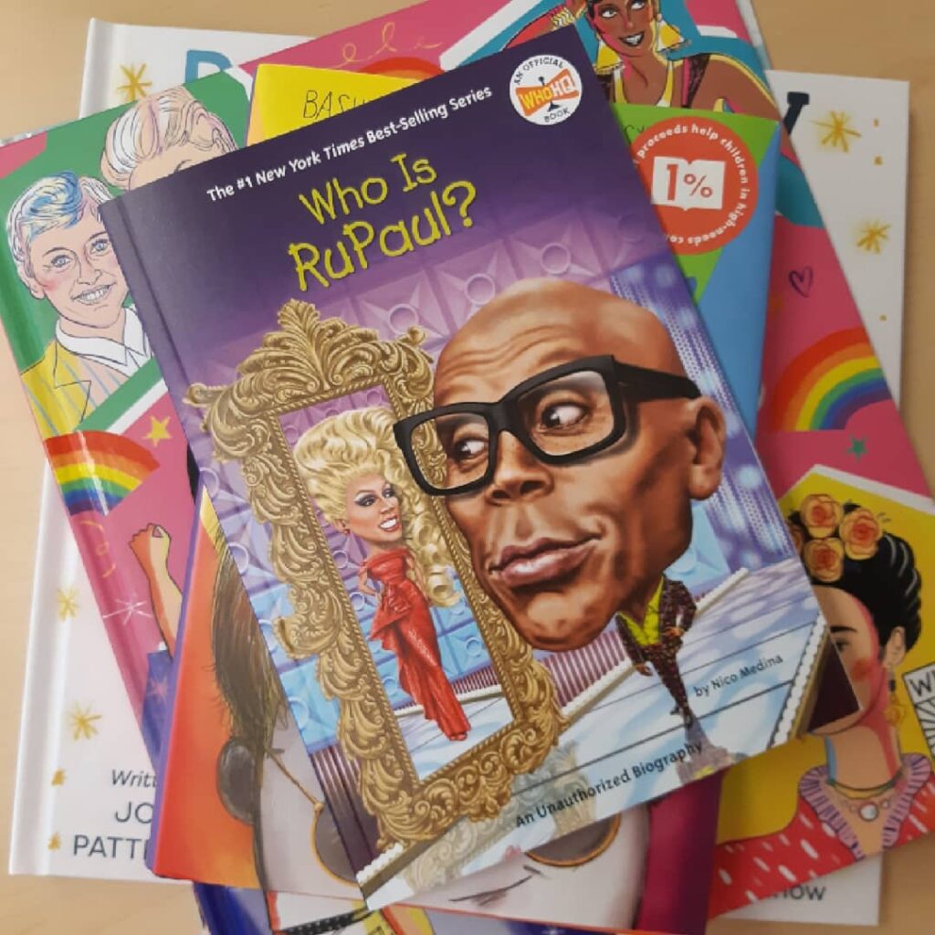 Who is Ru Paul? sits on top of a stack of children's books with LGBTQ themes. Queer Heroes and Born Ready peak out in the corners.